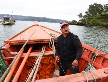 A fisherman sits in a boat on a river in Ecuador