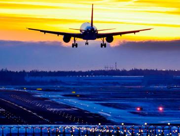 Plane above runway at sunrise or sunset